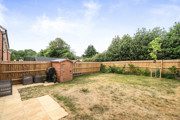 Back garden with grass lawn, wooden fence, shed, and surrounding trees.