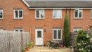 Rear view of a red brick terraced house with small patio and plants.