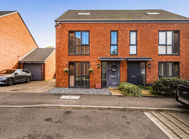 Semi-detached red brick house with driveway and parking spaces.