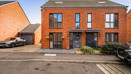 Semi-detached red brick house with driveway and parking spaces.