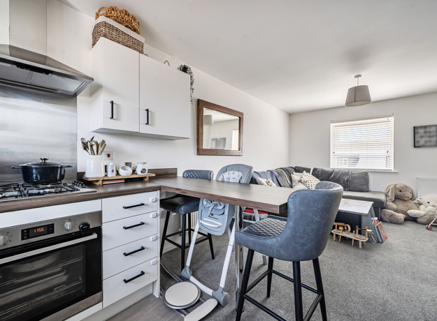 Open-plan kitchen and living area with breakfast bar and seating.