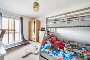 Bedroom with bunk bed, sports equpment, storage units and window.