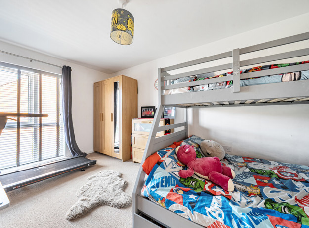 Bedroom with bunk bed, sports equpment, storage units and window.
