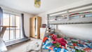 Bedroom with bunk bed, sports equpment, storage units and window.