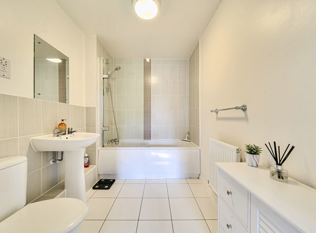 Bathroom with bath, shower screen, wash basin and radiator.