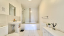 Bathroom with bath, shower screen, wash basin and radiator.
