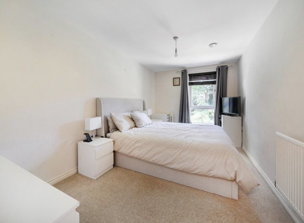 Bedroom with a double bed, bedside tables, wardrobe and window.