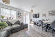 Living room with a corner sofa, dining table, TV and patio doors.