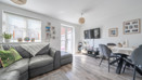 Living room with a corner sofa, dining table, TV and patio doors.