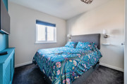Bedroom with patterned bedspread, wall-mounted TV and window.