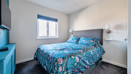 Bedroom with patterned bedspread, wall-mounted TV and window.