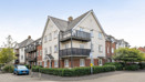 Exterior view of apartment building with balconies and parking area.