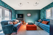 Living room with sofas, television, window, patio doors and red footstool.