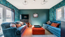 Living room with sofas, television, window, patio doors and red footstool.