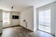 Dining area with wall-mounted TV, windows and wood-effect flooring.