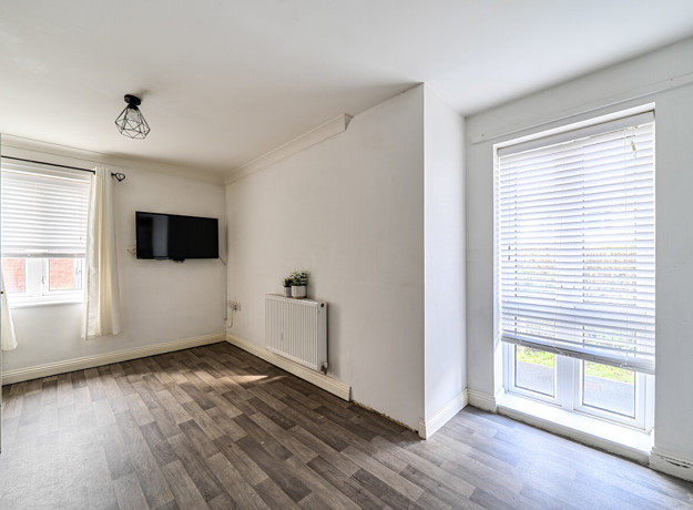 Dining area with wall-mounted TV, windows and wood-effect flooring.