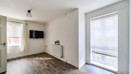 Dining area with wall-mounted TV, windows and wood-effect flooring.