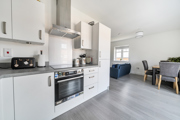 Open plan kitchen and dining area with appliances, table, and chairs visible.