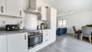 Open plan kitchen and dining area with appliances, table, and chairs visible.