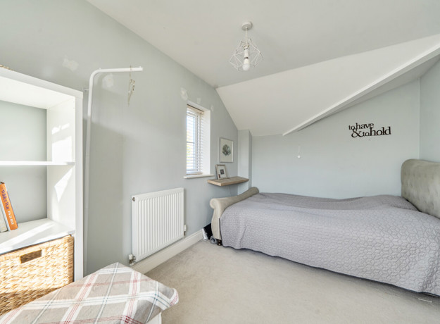 Bedroom with double bed, radiator and sloped ceiling.