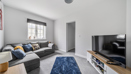 Living room with grey sofa, TV unit, and window with natural light.