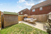 Small garden with lawn, shed, patio seating, and fenced boundaries.