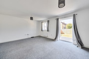 Living area with grey carpet and patio doors to the garden.