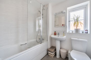 Bathroom with bath, shower over bath, toilet and sink.