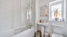 Bathroom with bath, shower over bath, toilet and sink.