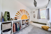 Bedroom with sun mural, storage, floorbed and window.