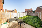 Rear garden with lawn, patio seating area and fenced boundaries.