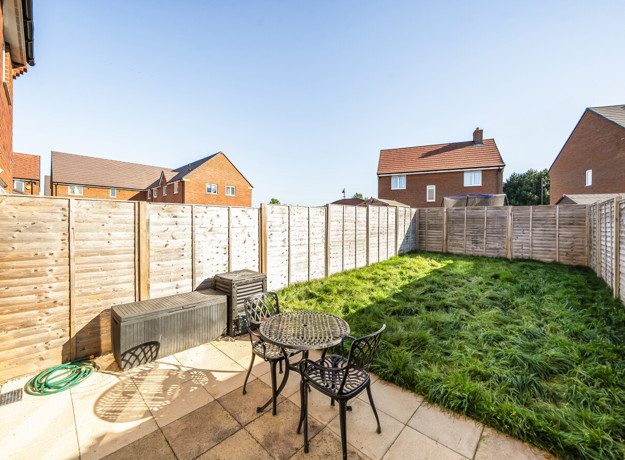 Rear garden with lawn, patio seating area and fenced boundaries.
