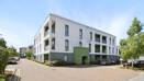 Apartment building exterior with windows, balconies, and paved walkway.