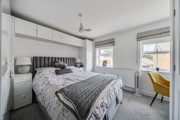 Double bedroom with bed, fitted storage and windows with blinds.