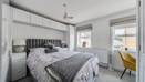 Double bedroom with bed, fitted storage and windows with blinds.