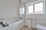 Family bathroom with bathtub, sink, toilet, and frosted window on a white wall.