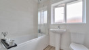 Family bathroom with bathtub, sink, toilet, and frosted window on a white wall.