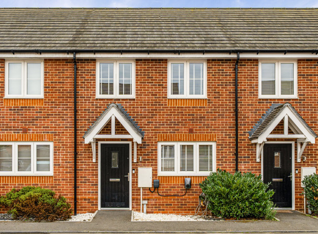 Red-brick terraced houses with front gardens and black front doors.
