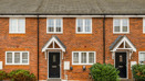 Red-brick terraced houses with front gardens and black front doors.