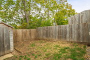 Enclosed rear garden with wooden fencing and trees behind fence.