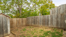 Enclosed rear garden with wooden fencing and trees behind fence.