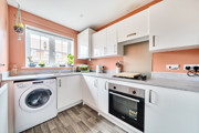 Kitchen with fitted units, washing machine, oven and window.