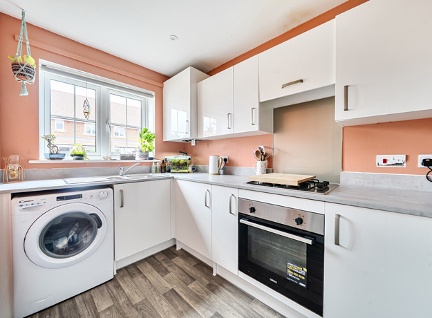 Kitchen with fitted units, washing machine, oven and window.