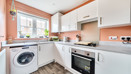 Kitchen with fitted units, washing machine, oven and window.