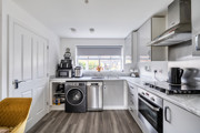 Kitchen with fitted units, appliances, wooden-effect floor and window.