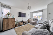 Living room with sofas, wall-mounted television and wooden sideboard.