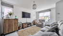 Living room with sofas, wall-mounted television and wooden sideboard.