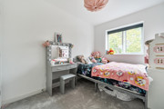 Children's bedroom with a single bed, dressing table and window.