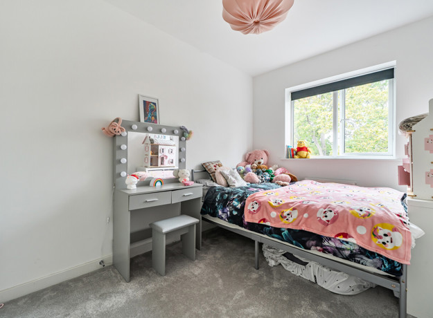 Children's bedroom with a single bed, dressing table and window.