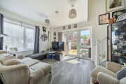Bright living room with sofas, large windows, TV and doors opening to the garden.
